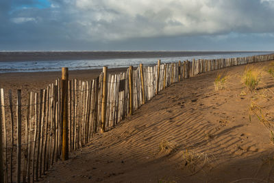 Wooden posts on beach against sky