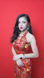 Beautiful young woman standing against red background