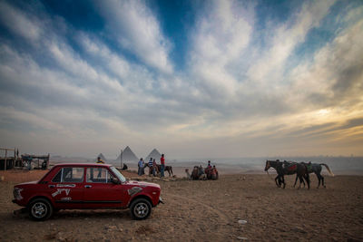 People on beach against sky during sunset