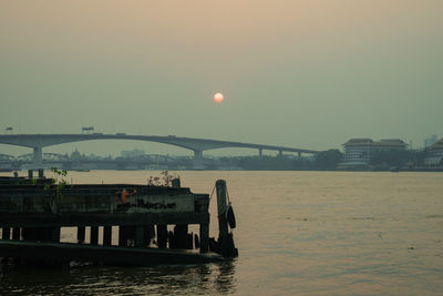 Bridge over river against sky during sunset