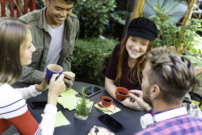 Portrait of smiling friends toasting drinks on table