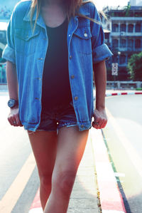 Midsection of woman wearing hot pants walking on road in city