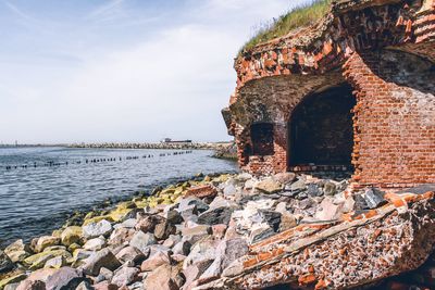 Old building by sea against sky