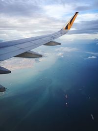 Close-up of airplane flying over water against sky