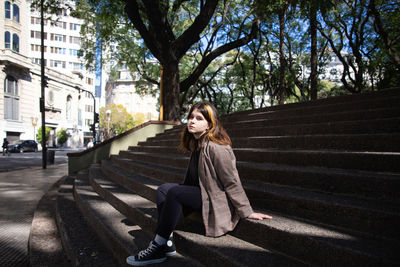 Woman sitting on staircase in city