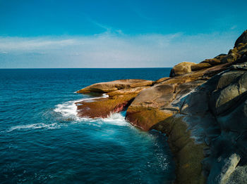 Rock formations by sea against blue sky