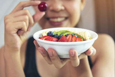 Midsection of woman holding fruits in bowl