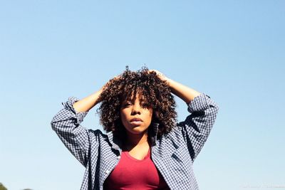 Low angle view of young woman against clear sky