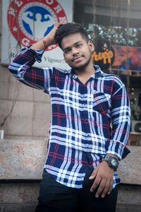 Portrait of young man standing against wall