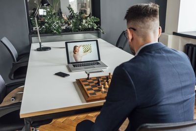 Businessman learning chess online through laptop at office