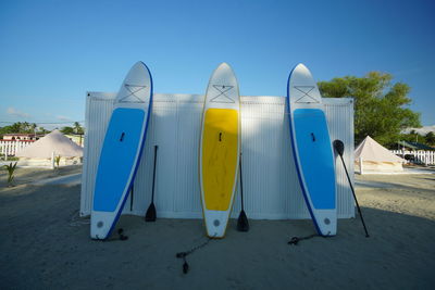 Surfboards on beach against blue sky
