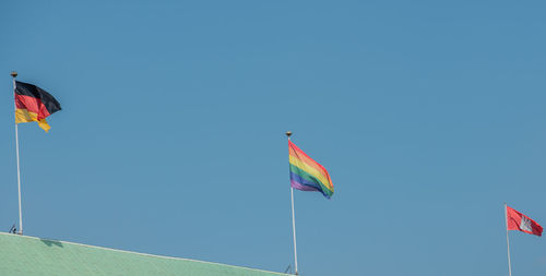 Low angle view of rainbow flags against sky