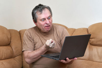 Young man using mobile phone while sitting on sofa at home