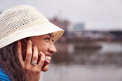 Close-up of smiling woman talking on phone by river