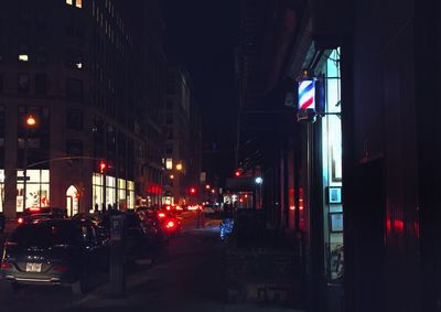 Illuminated road amidst buildings in city at night