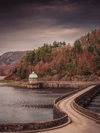 Bridge curving over a dam in the autumnal elan valley of wales uk