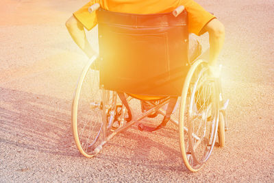 Rear view of man sitting on wheelchair during sunny day
