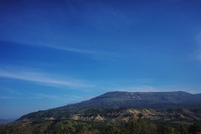 Scenic view of mountains against blue sky