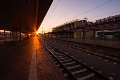 Empty railroad station platform against sky during sunset