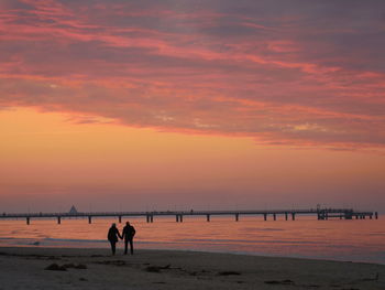 Silhouette man on beach against orange sky