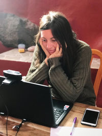 Woman using phone while sitting on table