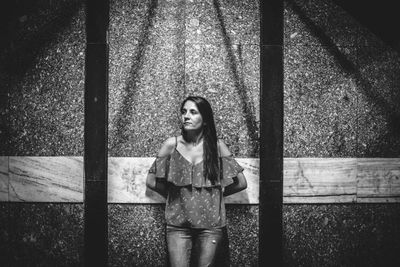 Young woman standing against wall