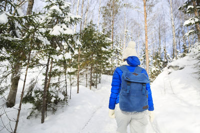 Rear view of man hiking on snow covered forest