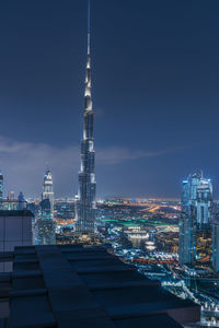 Illuminated tower in city against sky at night