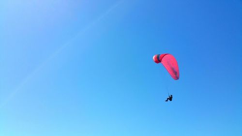 Low angle view of person paragliding against clear blue sky