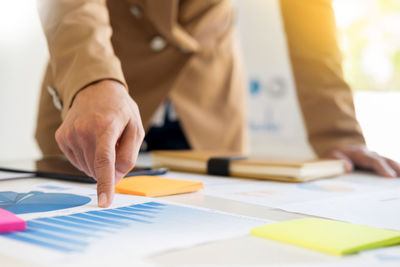 Midsection of businessman analyzing documents on table at office