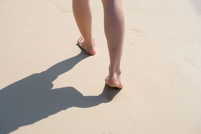 Low section of woman legs on sand at beach