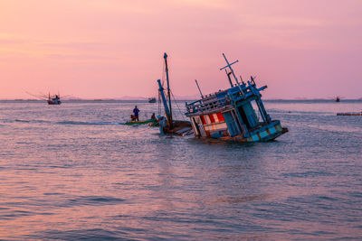 Fishing boat in sea against sky during sunset