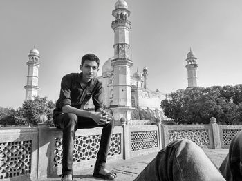 Young man sitting against clear sky