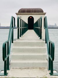 Rear view of man on pier by sea against sky