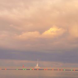 Boats in sea against cloudy sky