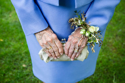 Grandmothers aged hands with a corsage holding a clutch at wedding