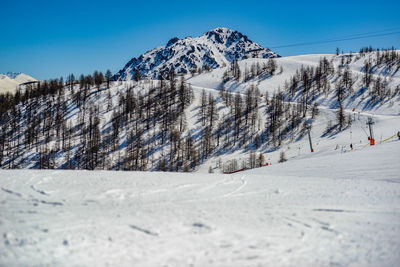 Scenic view of snow covered mountains against clear blue sky