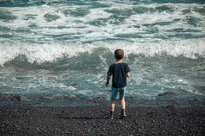 Rear view of boy standing at beach