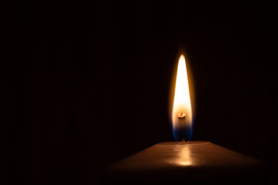 Close-up of lit candle in darkroom