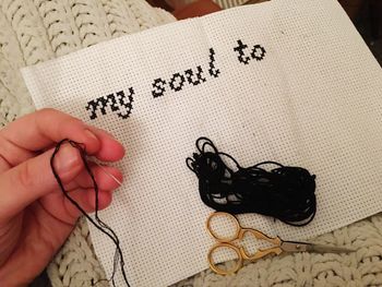 Cropped hand of woman writing with wool on fabric