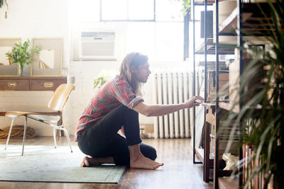 Side view of man looking at books on shelves in home