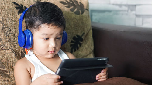 Cute boy looking away while using mobile phone