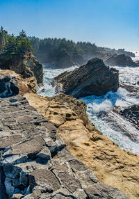 A shoreline with rock formations and crashing waves at shore acres state park in oregon state.