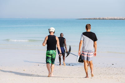 Three man walking towards the sea with efoil surfboard