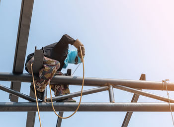 A welder working on a high rooftop for a new building.