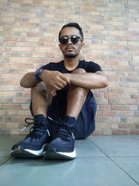 Portrait of young man sitting on wall