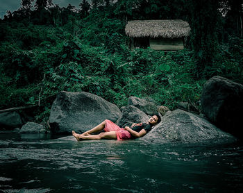 Man relaxing by lake on rock