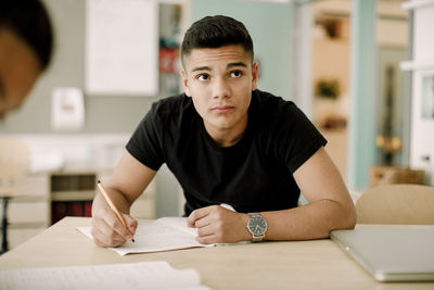 Contemplating teenage boy looking away while sitting in classroom