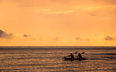 Silhouette people in boat on sea against sky during sunset