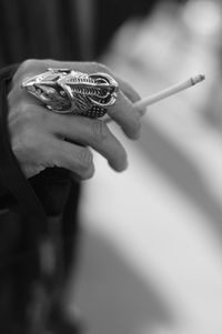 Cropped hand with knuckle ring holding cigarette